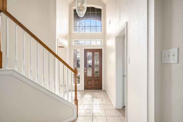 entryway featuring a healthy amount of sunlight, a high ceiling, and light tile patterned floors