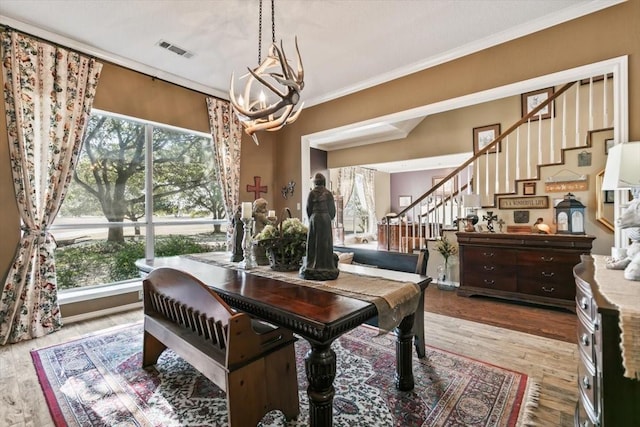 dining room with hardwood / wood-style floors, crown molding, a wealth of natural light, and a chandelier