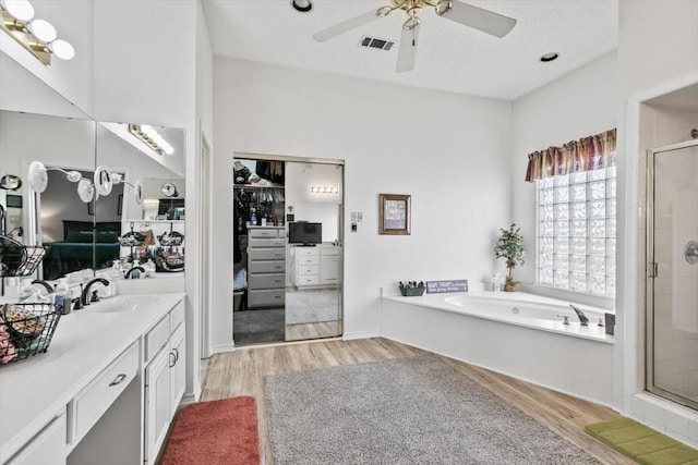 bathroom featuring hardwood / wood-style flooring, ceiling fan, vanity, and shower with separate bathtub