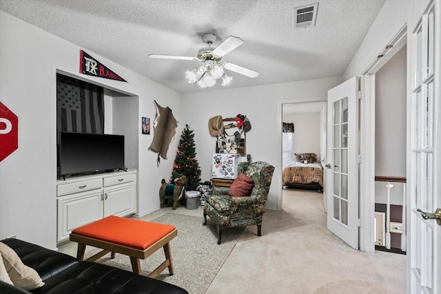 living room with light carpet, a textured ceiling, french doors, and ceiling fan