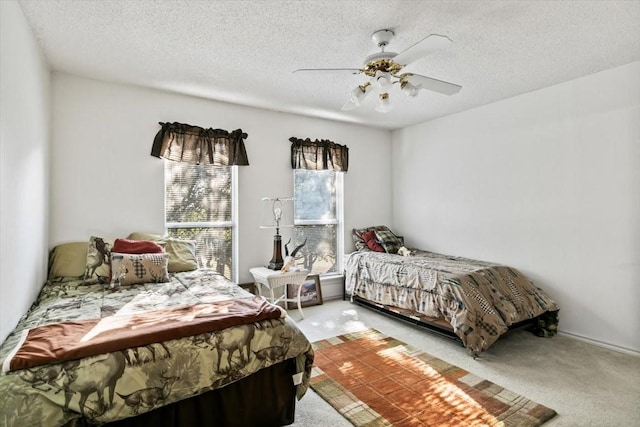 carpeted bedroom featuring ceiling fan and a textured ceiling