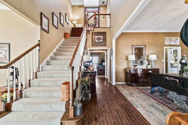 staircase featuring wood-type flooring and a towering ceiling