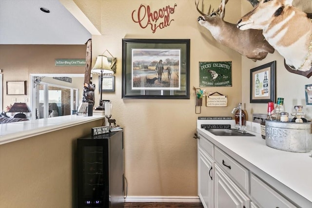 bar with wine cooler, sink, and white cabinets