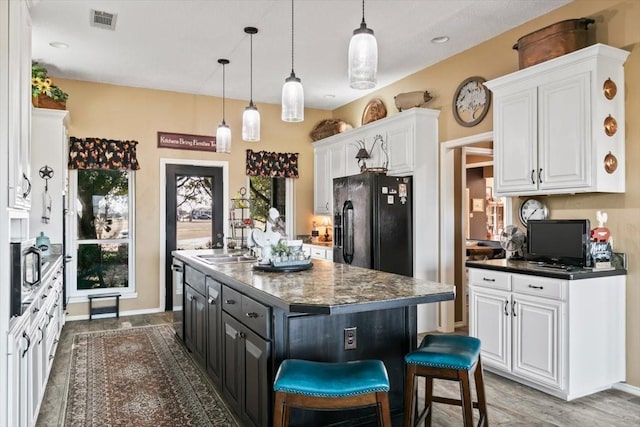 kitchen featuring pendant lighting, black refrigerator with ice dispenser, a kitchen island, and white cabinets