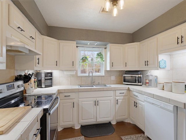 kitchen featuring sink, white cabinetry, tile counters, stainless steel appliances, and decorative backsplash