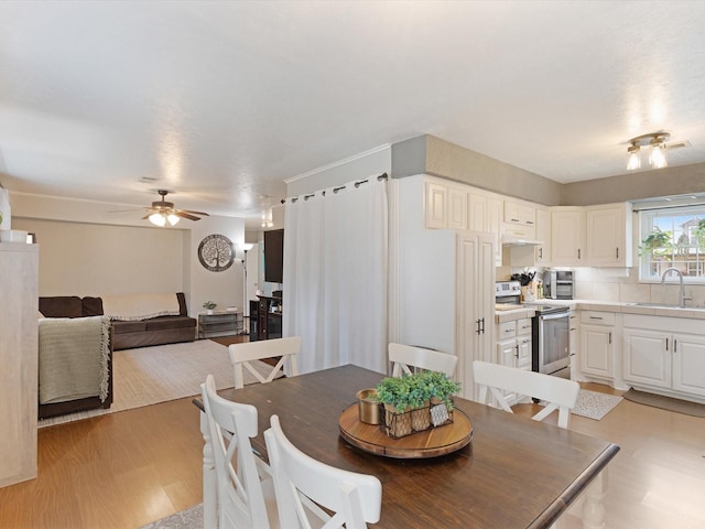 dining space with sink, ceiling fan, and light wood-type flooring