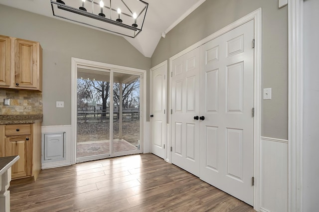 doorway to outside featuring hardwood / wood-style flooring, lofted ceiling, and a chandelier