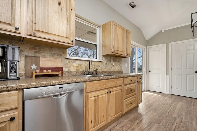 kitchen featuring vaulted ceiling, light brown cabinetry, sink, stainless steel dishwasher, and light wood-type flooring