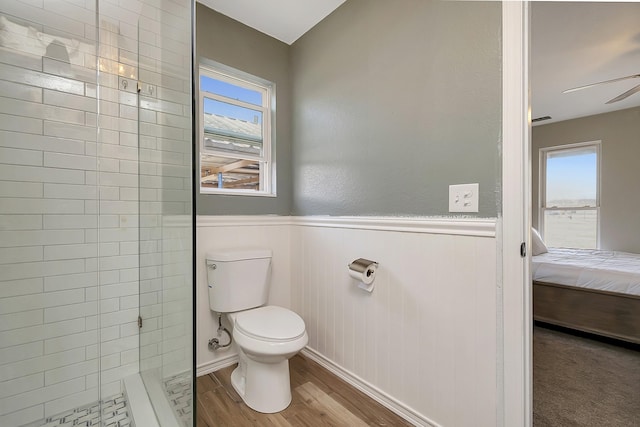 bathroom featuring ceiling fan, toilet, hardwood / wood-style floors, and a tile shower