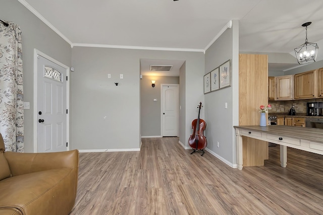 living room with an inviting chandelier, ornamental molding, and light wood-type flooring