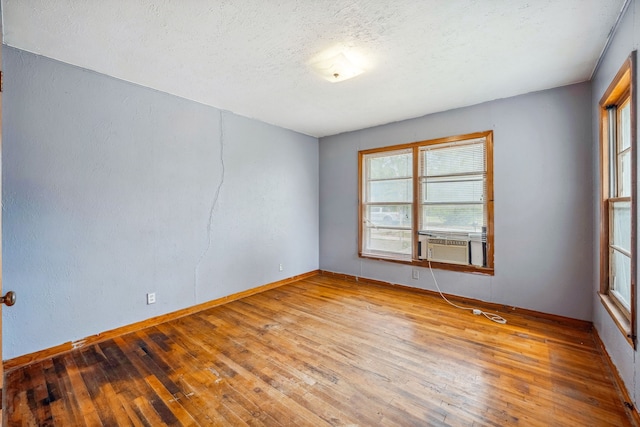 spare room featuring cooling unit, wood-type flooring, and a textured ceiling