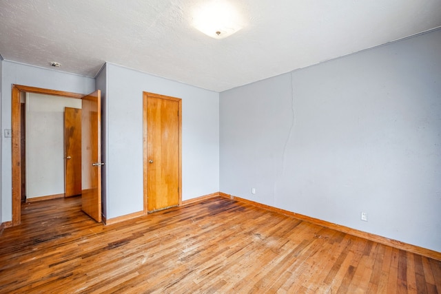 unfurnished bedroom featuring hardwood / wood-style floors, a closet, and a textured ceiling