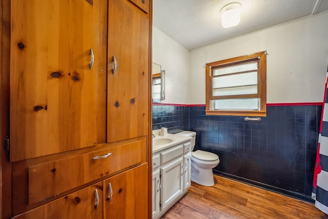 bathroom featuring hardwood / wood-style flooring, tile walls, vanity, a textured ceiling, and toilet