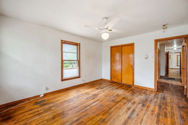 unfurnished bedroom featuring hardwood / wood-style floors, a closet, and ceiling fan