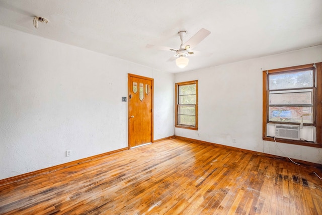 empty room featuring hardwood / wood-style flooring, ceiling fan, and cooling unit