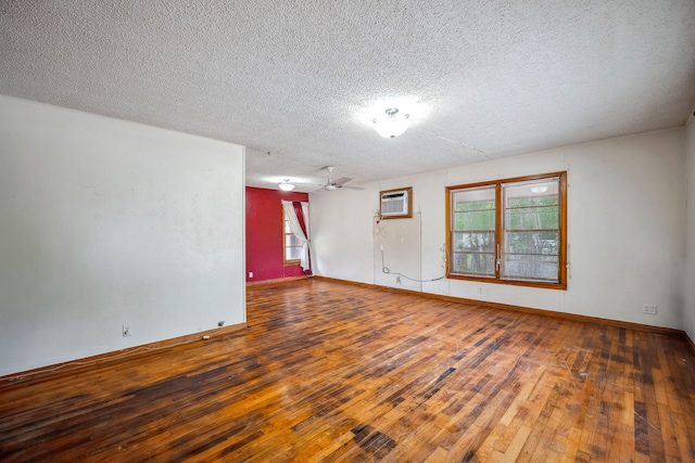 empty room with ceiling fan, a wall mounted air conditioner, wood-type flooring, and a textured ceiling