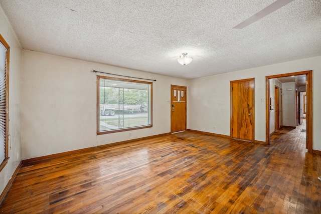 unfurnished room featuring a textured ceiling and dark hardwood / wood-style flooring