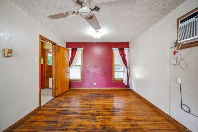 spare room with ceiling fan, dark hardwood / wood-style floors, a textured ceiling, and an AC wall unit