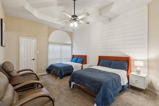 carpeted bedroom featuring ceiling fan and a tray ceiling