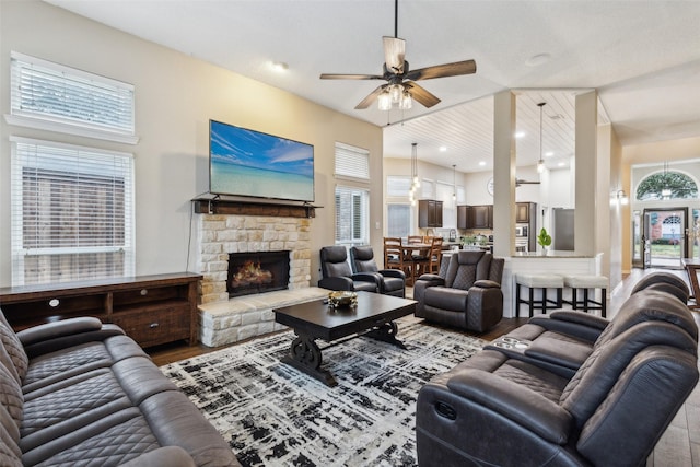 living room with ceiling fan, a stone fireplace, and hardwood / wood-style floors