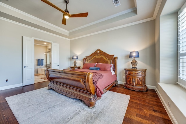 bedroom with connected bathroom, crown molding, dark wood-type flooring, and a raised ceiling