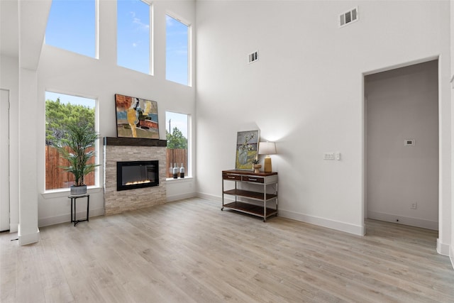 unfurnished living room featuring a wealth of natural light, light hardwood / wood-style flooring, and a stone fireplace