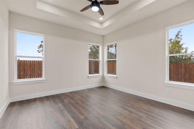 unfurnished room featuring a raised ceiling, dark wood-type flooring, and ceiling fan