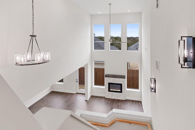 living room with dark hardwood / wood-style floors, a stone fireplace, and a high ceiling