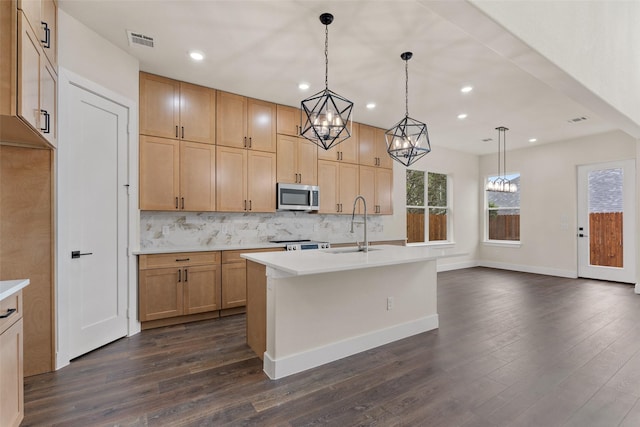 kitchen featuring a kitchen island with sink, sink, stainless steel appliances, and hanging light fixtures