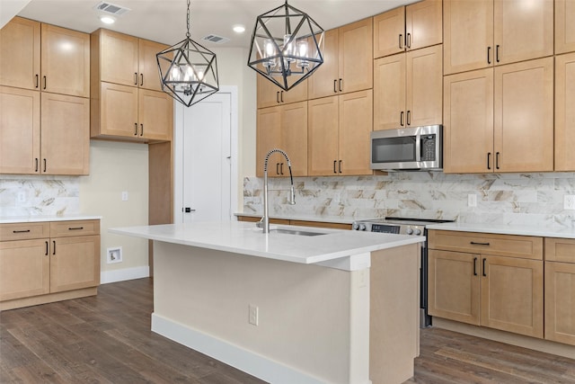 kitchen featuring decorative light fixtures, sink, a kitchen island with sink, stainless steel appliances, and light brown cabinets