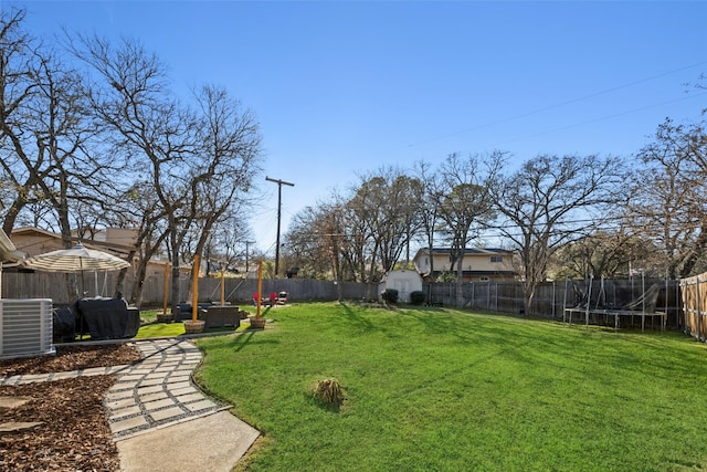 view of yard with a trampoline, central AC unit, and a storage unit