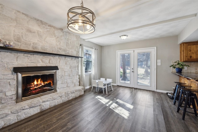 living room featuring an inviting chandelier, a fireplace, dark wood-type flooring, and french doors