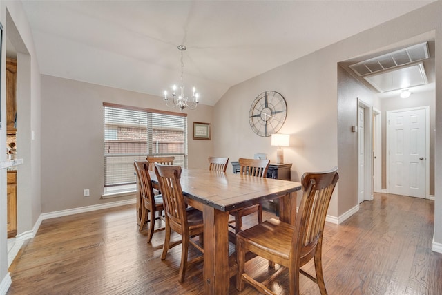 dining area with an inviting chandelier, lofted ceiling, and hardwood / wood-style floors