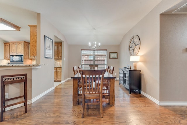 dining room featuring lofted ceiling, hardwood / wood-style floors, and a notable chandelier