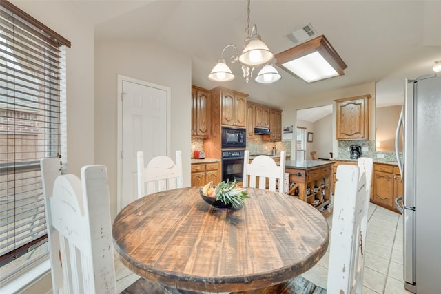 tiled dining space featuring an inviting chandelier and vaulted ceiling