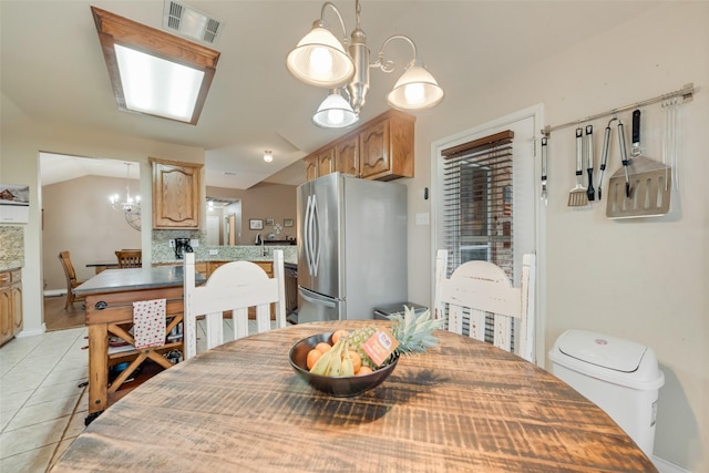 tiled dining room with a notable chandelier and vaulted ceiling