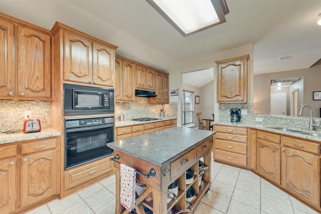 kitchen with light stone counters, light tile patterned floors, sink, and black appliances