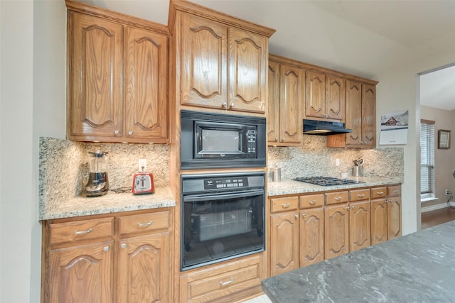 kitchen with tasteful backsplash, light stone countertops, and black appliances