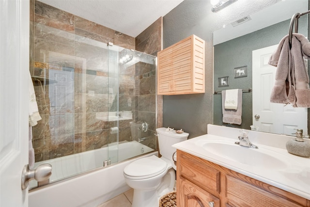 full bathroom featuring enclosed tub / shower combo, vanity, a textured ceiling, tile patterned floors, and toilet