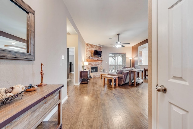 living room featuring a fireplace, light hardwood / wood-style floors, and ceiling fan