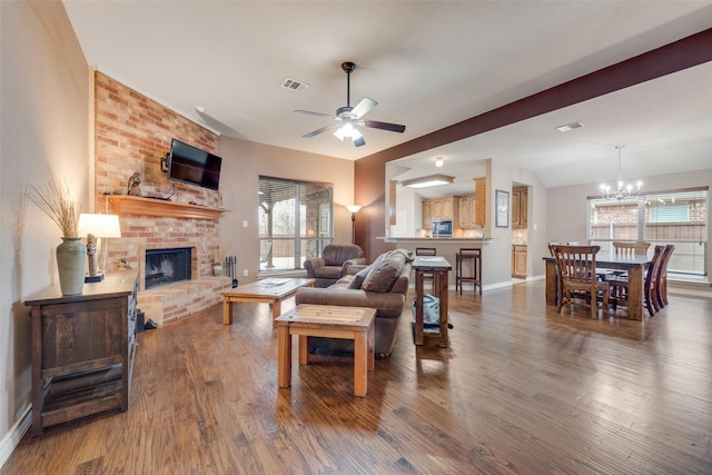 living room with hardwood / wood-style flooring, lofted ceiling, a fireplace, and ceiling fan with notable chandelier