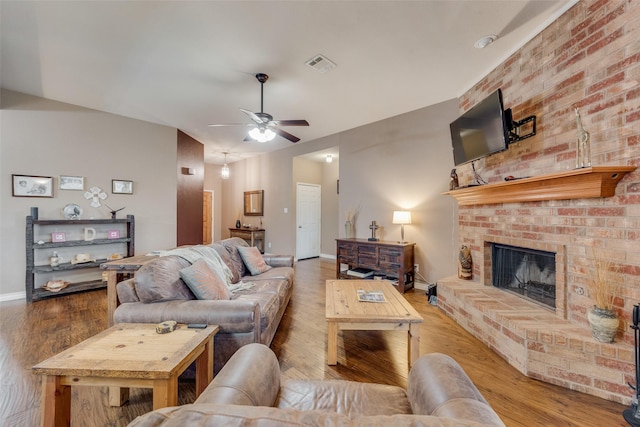 living room with ceiling fan, a fireplace, and light hardwood / wood-style floors