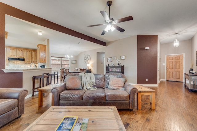 living room with ceiling fan with notable chandelier, lofted ceiling with beams, and light wood-type flooring