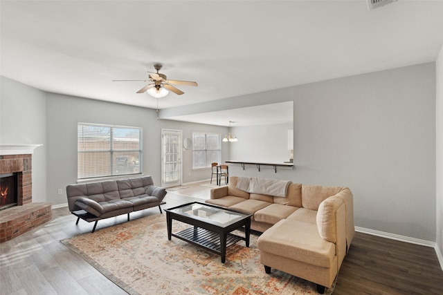 living room featuring ceiling fan, hardwood / wood-style floors, and a brick fireplace