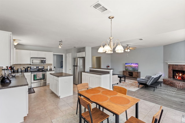 dining space with light tile patterned flooring, sink, a notable chandelier, and a fireplace