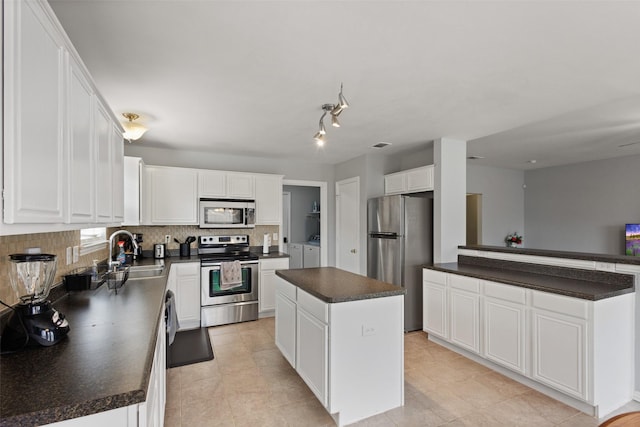 kitchen featuring a kitchen island, appliances with stainless steel finishes, sink, white cabinets, and decorative backsplash