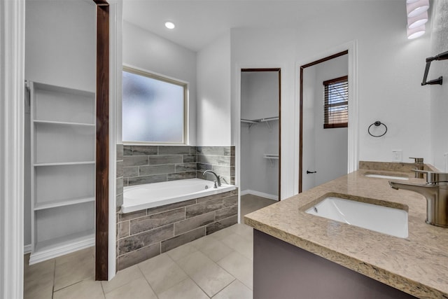 bathroom with tile patterned floors, vanity, and tiled tub