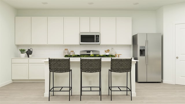 kitchen featuring a breakfast bar, backsplash, white cabinets, a center island, and stainless steel refrigerator with ice dispenser