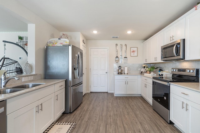 305 Grenada Lake Dr, Princeton, TX 75407 - kitchen with sink, tasteful backsplash, light wood-type flooring, appliances with stainless steel finishes, and white cabinets