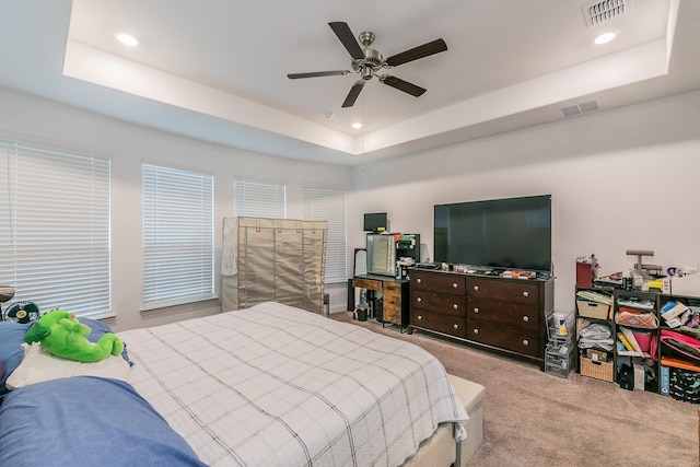 bedroom featuring light colored carpet, a raised ceiling, and ceiling fan